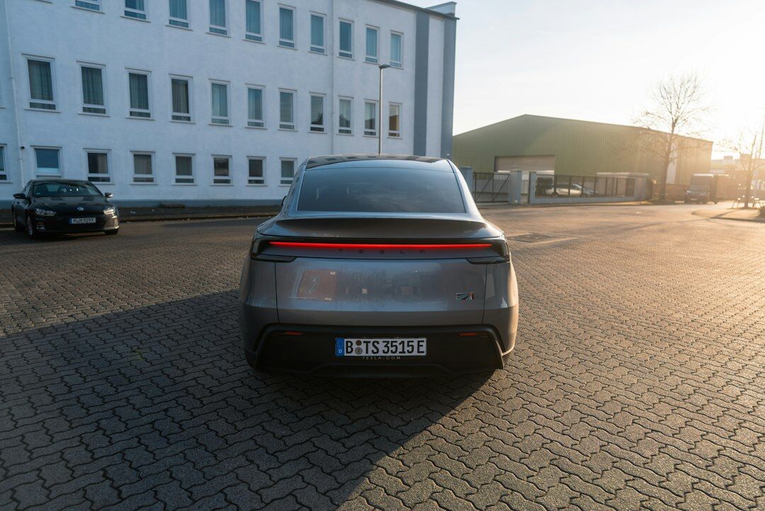 White Tesla Model Y electric SUV parked in a modern driveway with solar panels