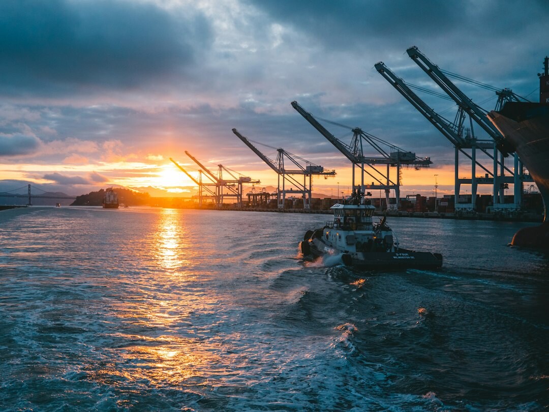 Cargo ship carrying containers and vehicles at a port at dusk