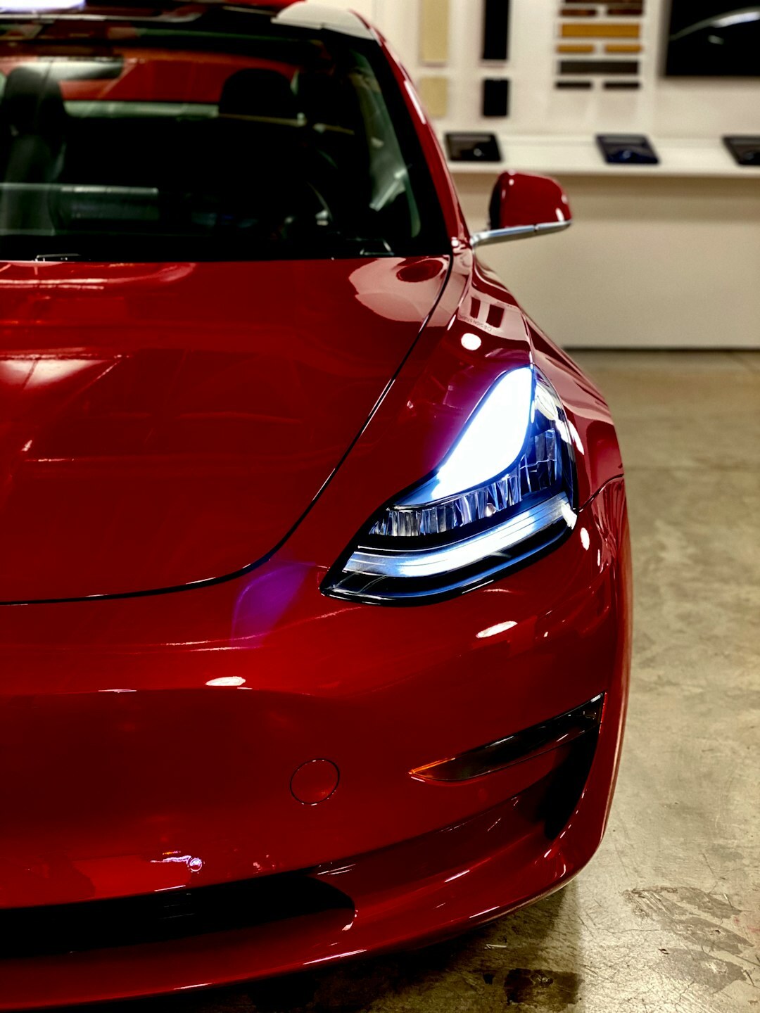 Red Tesla Model 3 electric sedan at a modern charging station